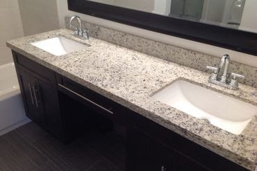 A granite countertop in a bathroom with two sinks.