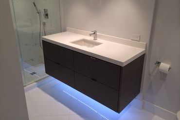 White marble bathroom countertops with a blue glow underneath the cabinets.
